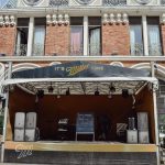 Palco de música vazio montado ao ar livre diante de um prédio histórico.