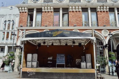 Palco de música vazio montado ao ar livre diante de um prédio histórico.