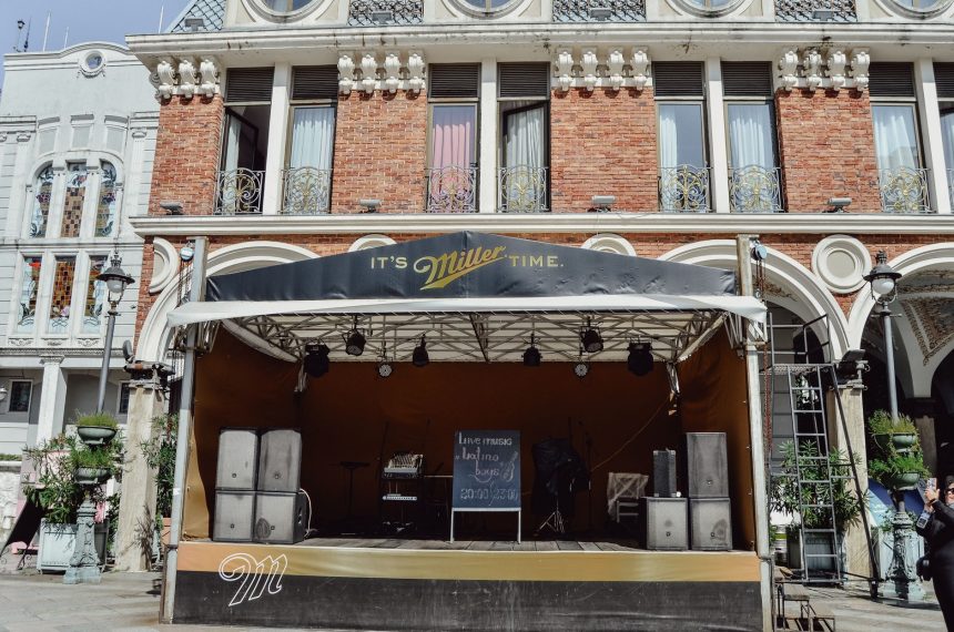 Palco de música vazio montado ao ar livre diante de um prédio histórico.