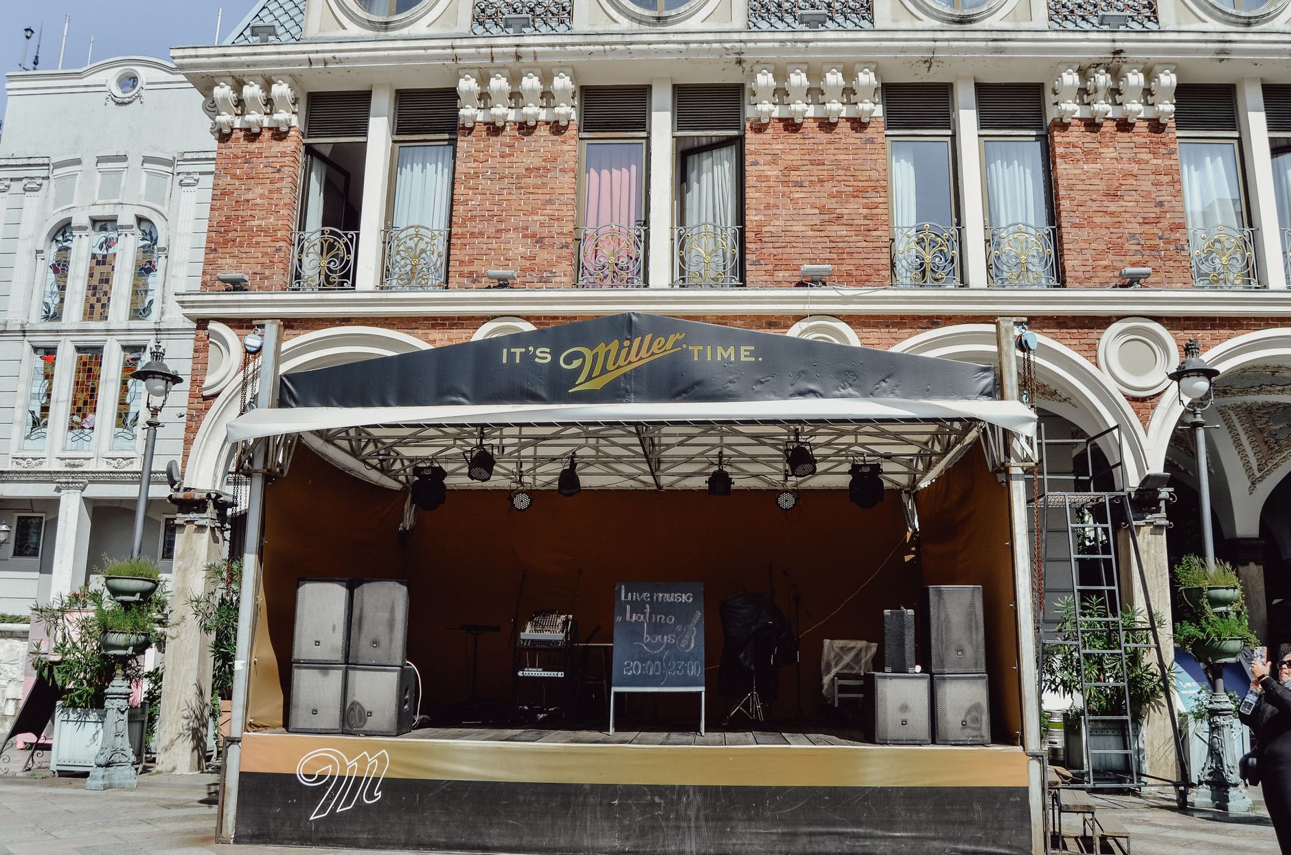 Palco de música vazio montado ao ar livre diante de um prédio histórico.