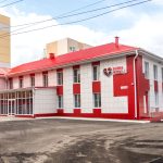 Fachada de uma unidade de saúde moderna, com estrutura em vermelho e branco.