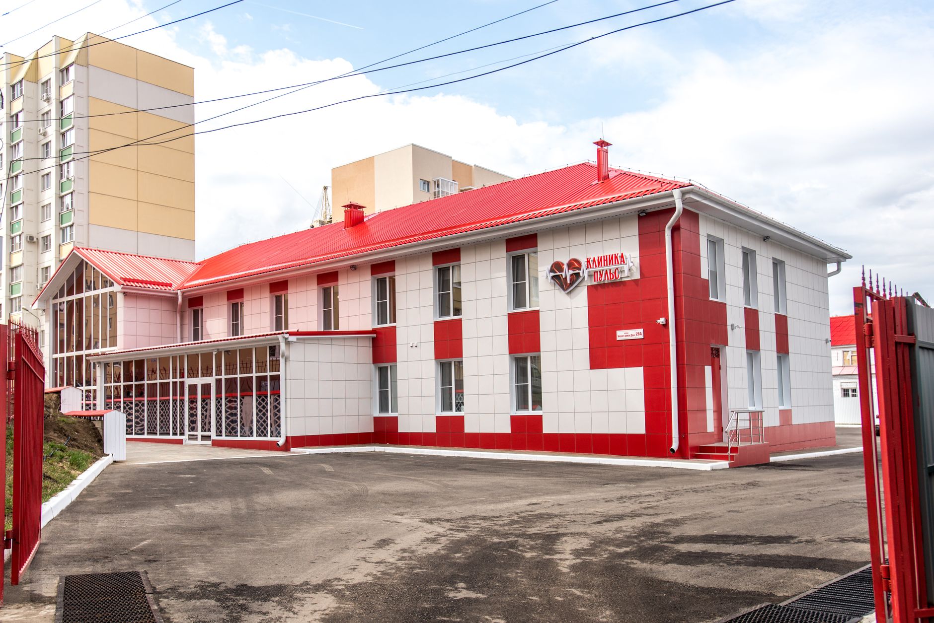 Fachada de uma unidade de saúde moderna, com estrutura em vermelho e branco.