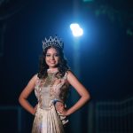 Mulher usando coroa e vestido elegante posa sob iluminação dramática durante a noite