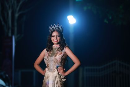 Mulher usando coroa e vestido elegante posa sob iluminação dramática durante a noite