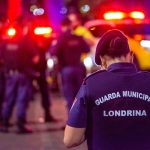 Agente da Guarda Civil Municipal permanece em serviço durante a noite em uma via urbana.