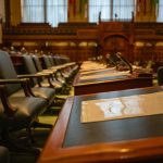 Plenário legislativo vazio, com fileiras de mesas equipadas com microfones.
