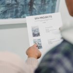 Mãos apontam detalhes de um documento de projeto cultural durante uma reunião.
