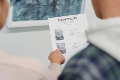 Mãos apontam detalhes de um documento de projeto cultural durante uma reunião.